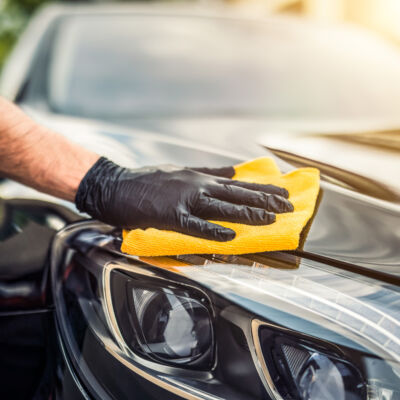 Car detailing - the man holds the microfiber in hand and polishes the car. Selective focus.